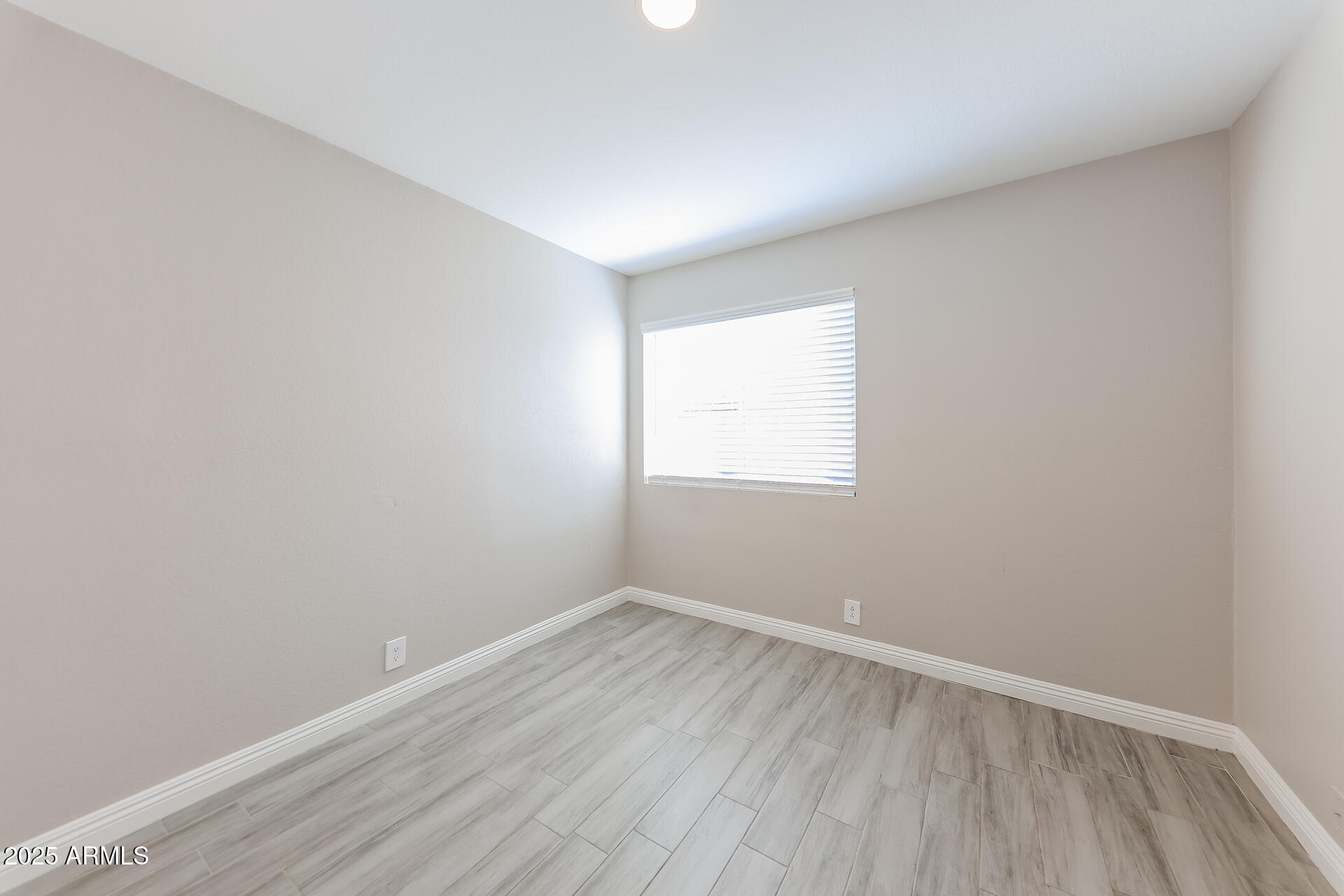 8833 West Monte Vista Road Phoenix, AZ 85037 - Photo 14 of 21 an empty room with wooden floor and windows