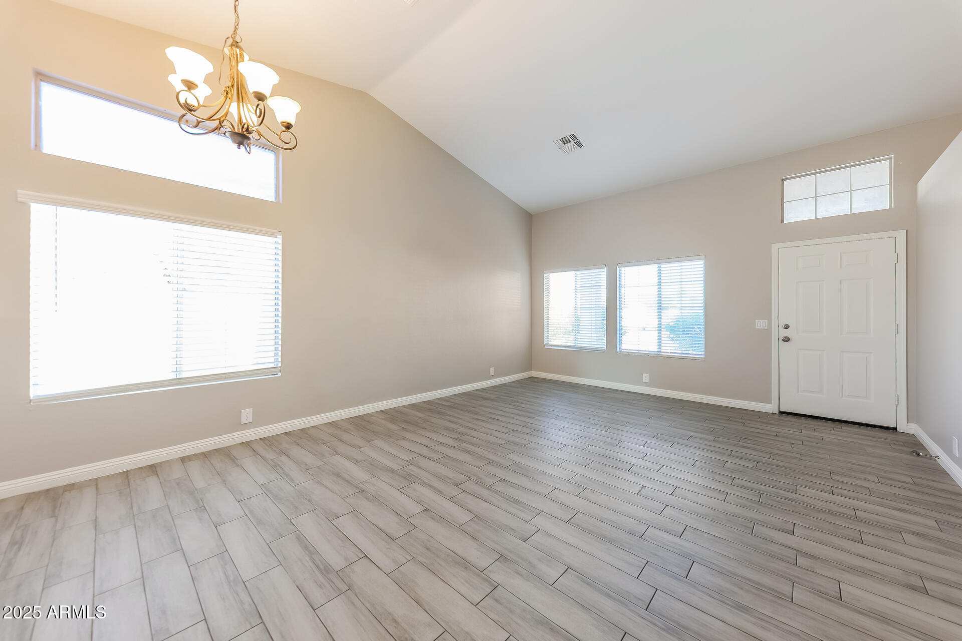 8833 West Monte Vista Road Phoenix, AZ 85037 - Photo 3 of 21 an empty room with wooden floor chandelier and windows