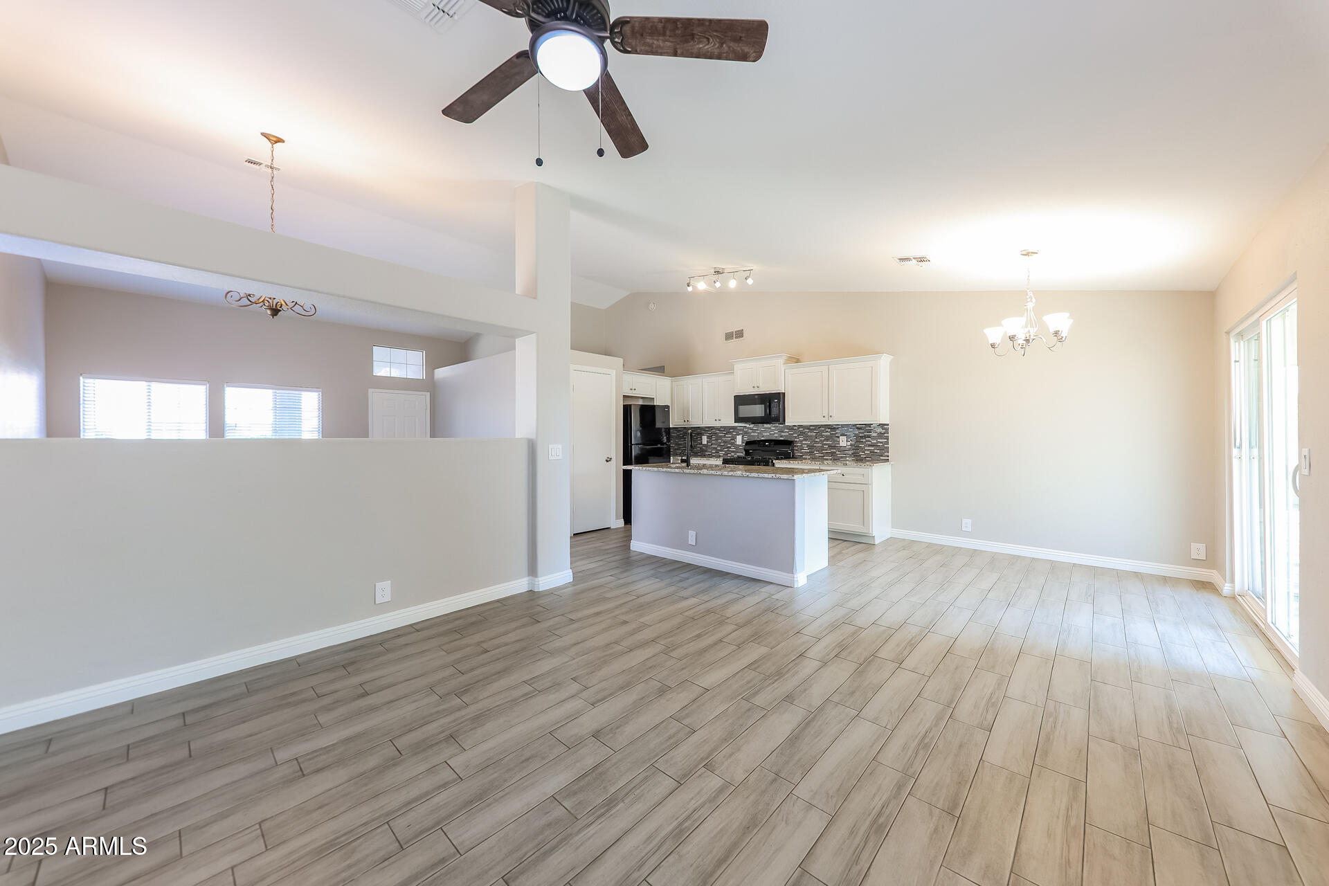 8833 West Monte Vista Road Phoenix, AZ 85037 - Photo 8 of 21 an empty room with wooden floor kitchen view and a window