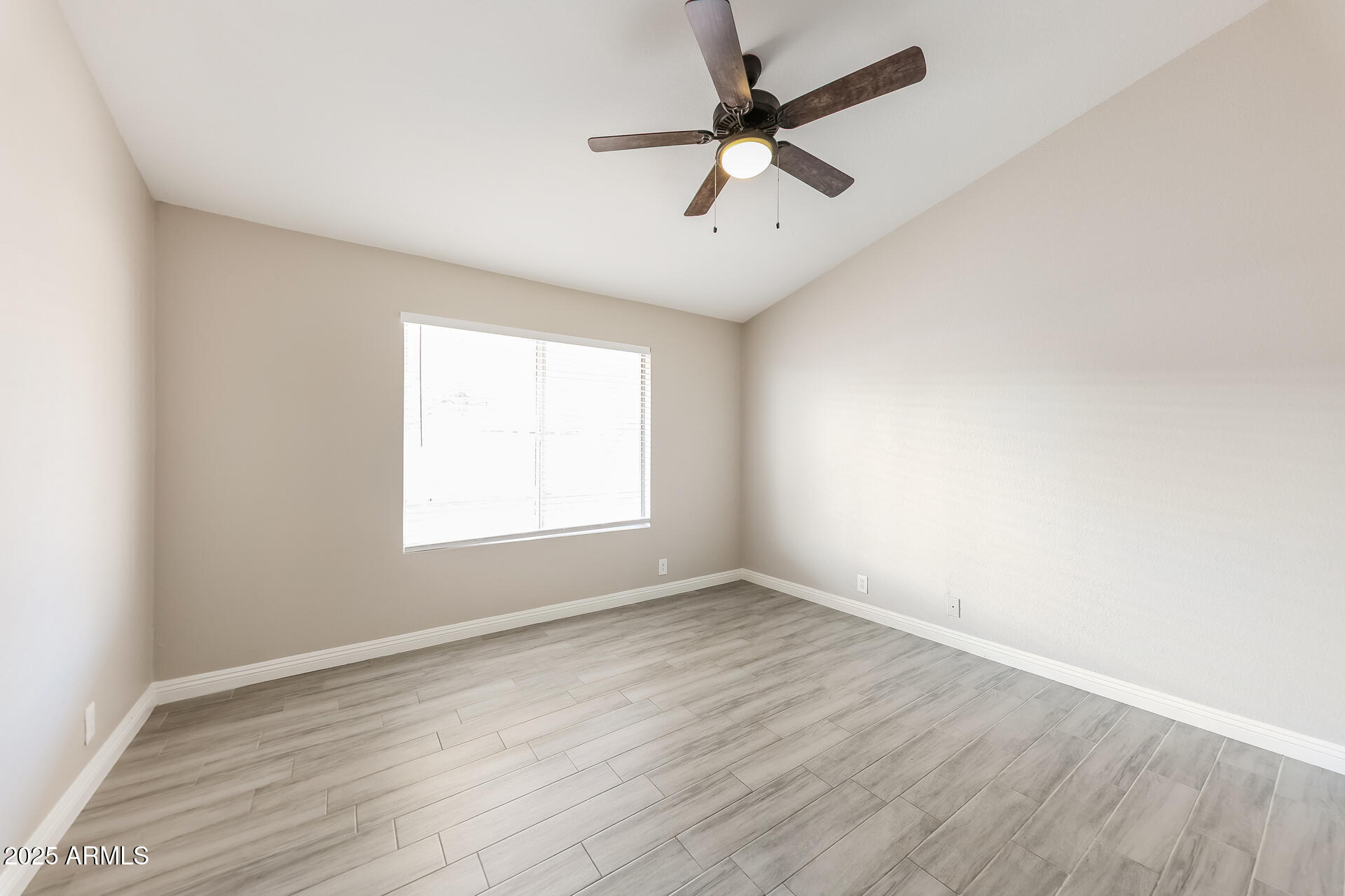 8833 West Monte Vista Road Phoenix, AZ 85037 - Photo 9 of 21 an empty room with wooden floor fan and windows
