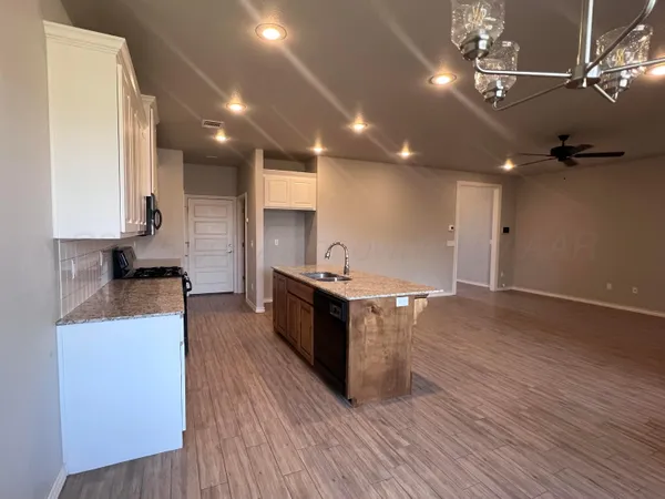 a large kitchen with stainless steel appliances granite countertop a large counter top a stove and a wooden floors