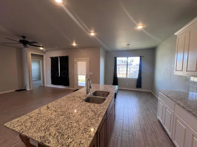 a kitchen with granite countertop white cabinets and a sink