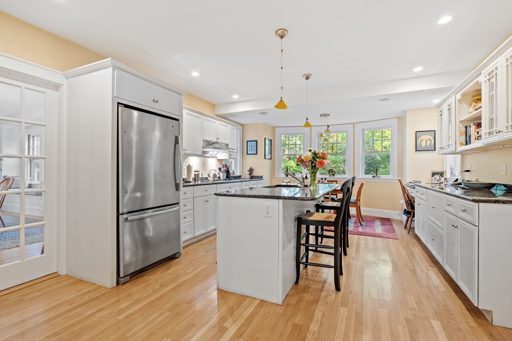 30 Burlington Street Lexington, MA 02420 - Photo 12 of 34 a kitchen with stainless steel appliances granite countertop a refrigerator a stove a sink dishwasher and a dining table with wooden floor