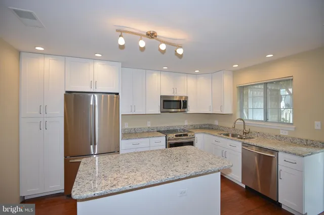 a kitchen with stainless steel appliances granite countertop a sink refrigerator and microwave