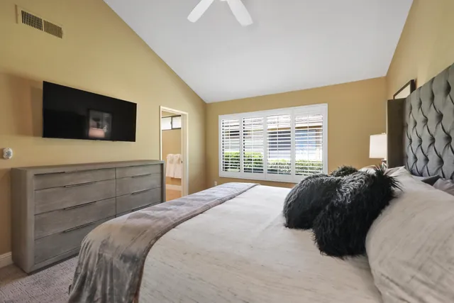 a bedroom with a bed and a flat tv screen on dresser