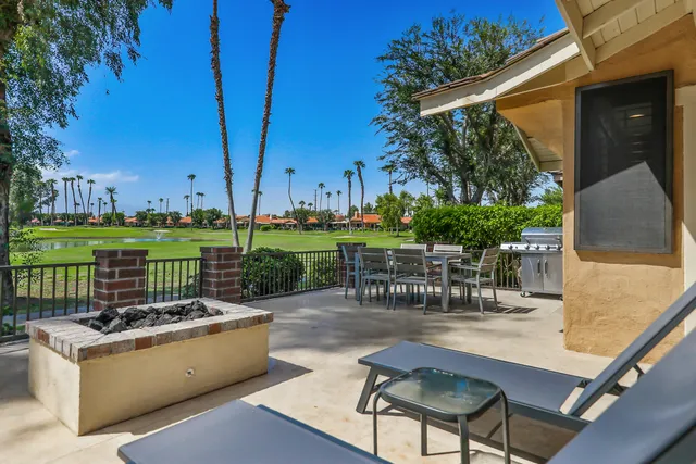 a view of a patio with couches chairs potted plants and a palm tree