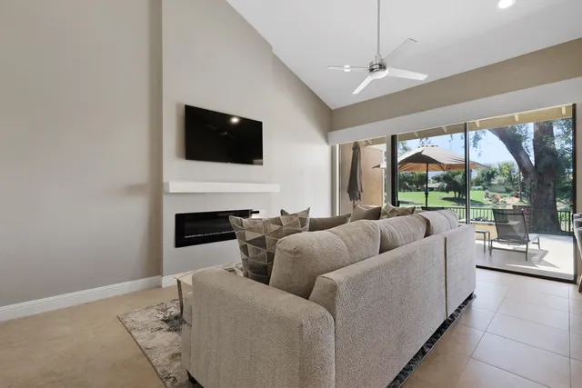 a living room with furniture a flat screen tv and a floor to ceiling window