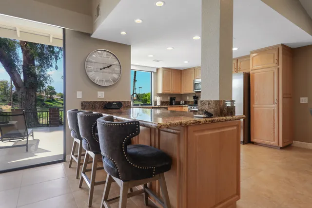 a living room with stainless steel appliances granite countertop furniture a fireplace a rug and a large window