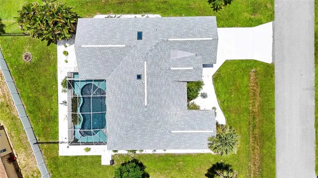 an aerial view of a house with swimming pool and large trees