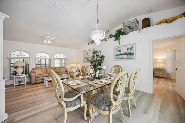 a dining room with wooden floor a chandelier a wooden table and chairs