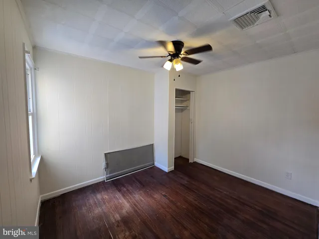 an empty room with wooden floor chandelier fan and closet