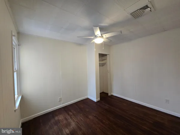 an empty room with wooden floor and ceiling fan