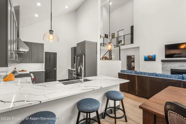 a kitchen with stainless steel appliances kitchen island granite countertop a dining table chairs and sink