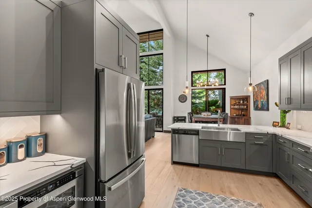 a kitchen with stainless steel appliances a refrigerator a sink a stove and chairs