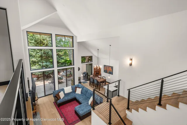 a living room with furniture floor to ceiling window and a flat screen tv