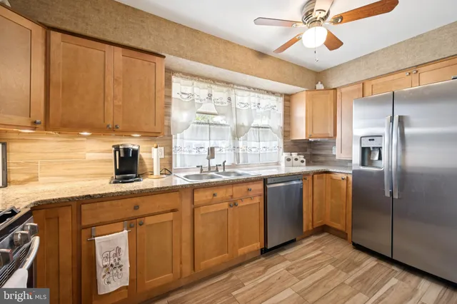 a kitchen with granite countertop a refrigerator a sink and dishwasher with wooden floor