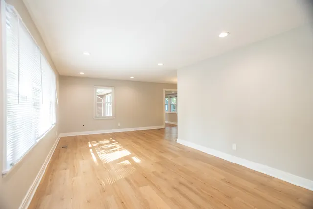 an empty room with wooden floor and windows