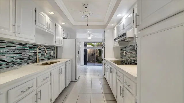 a large white kitchen with granite countertop a sink and dishwasher stove