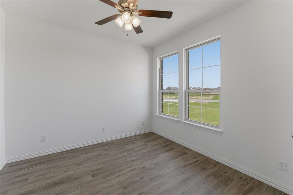 130 Fossil Canyon Drive Rhome, TX 76078 - Photo 6 of 25 Room featuring two large windows, wood-finish flooring, white baseboards, and a ceiling fan with integrated lighting