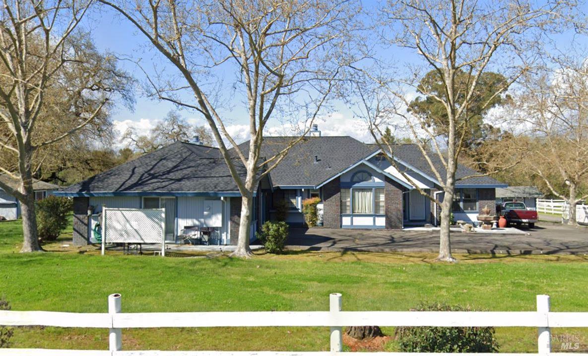 a front view of a house with a garden and trees