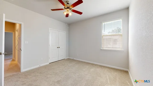 an empty room with a window and a fan