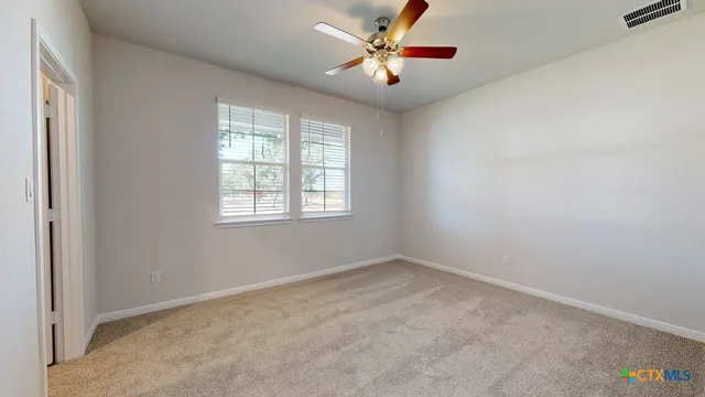 an empty room with closet and a ceiling fan