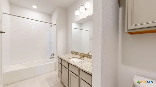 a bathroom with a granite countertop sink mirror and a bathtub