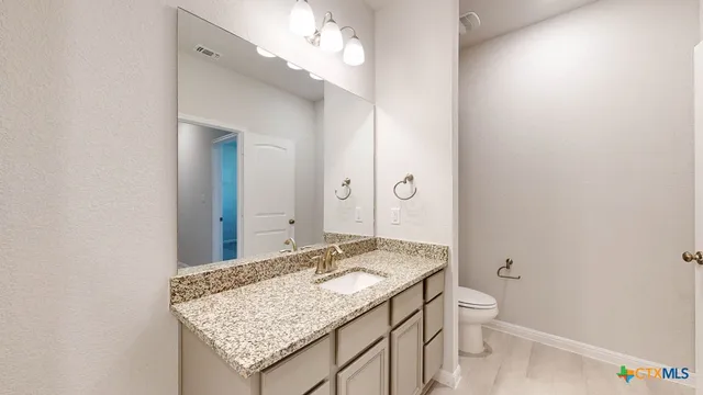 a bathroom with a granite countertop sink and a mirror
