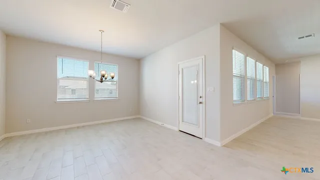an empty room with chandelier fan and windows