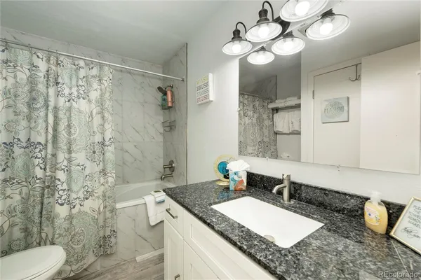 a bathroom with a granite countertop sink mirror vanity and toilet