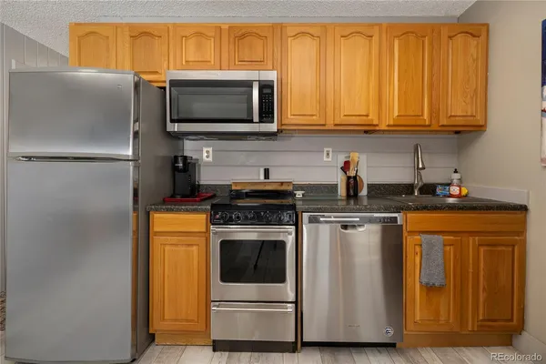 a kitchen with stainless steel appliances granite countertop a stove top oven microwave and refrigerator