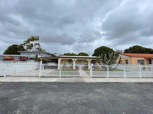 a view of house with a big yard and large tree