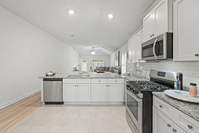 a kitchen with granite countertop white cabinets and stainless steel appliances