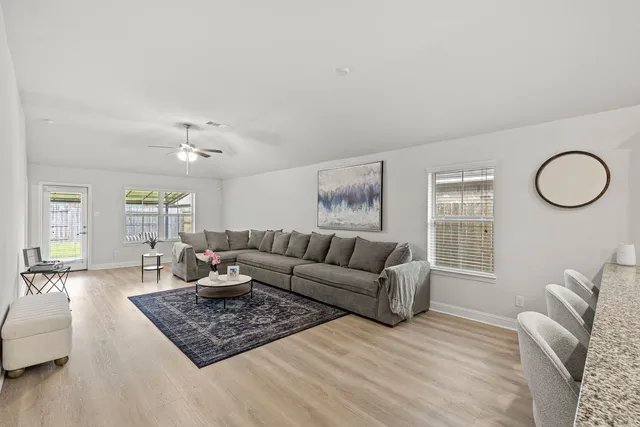 a kitchen with stainless steel appliances granite countertop a sink a stove a refrigerator and a dining table with wooden floor