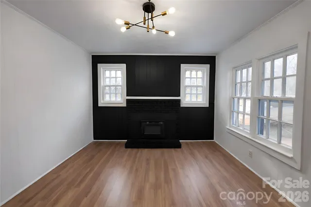 a big room with wooden floor a chandelier fan and windows