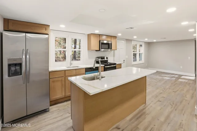 a kitchen with stainless steel appliances granite countertop a sink a refrigerator and a stove with wooden floor