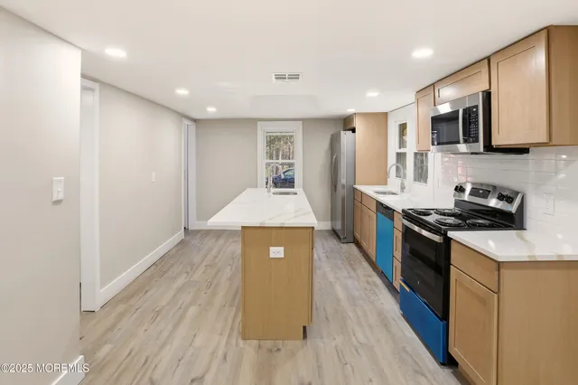 a large kitchen with stainless steel appliances granite countertop a stove a sink and a refrigerator