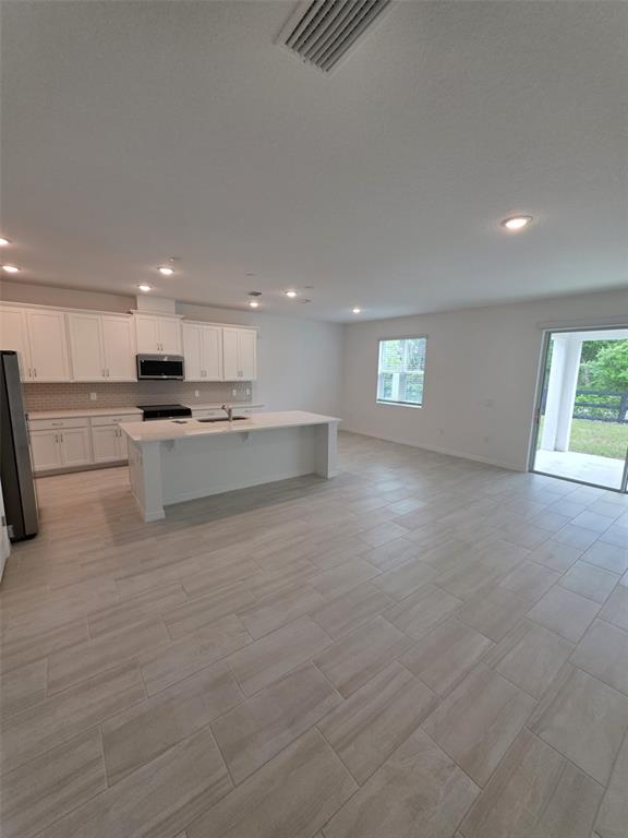 6008 Vision Road St. Cloud, FL 34771 - Photo 15 of 33 a large kitchen with stainless steel appliances granite countertop a stove a sink and a refrigerator