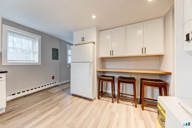 a kitchen with granite countertop a stove a refrigerator and a white cabinets