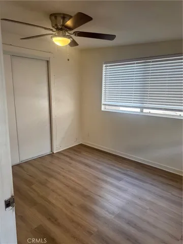 a view of empty room with wooden floor and fan