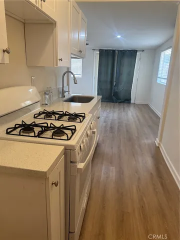a kitchen with granite countertop a stove and a wooden floor
