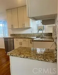 a kitchen with kitchen island granite countertop a sink a stove and cabinets