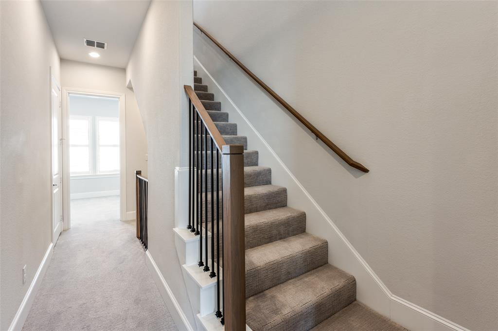 5421 Patterson Street Irving, TX 75039 - Photo 24 of 32 Staircase featuring wood-finish newel posts and handrails, black metal balusters, and carpeted treads