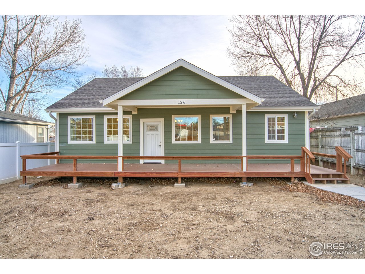 a view of a house that has a small deck and a wooden fence