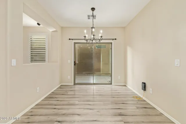 a view of a hallway with wooden floor and a chandelier