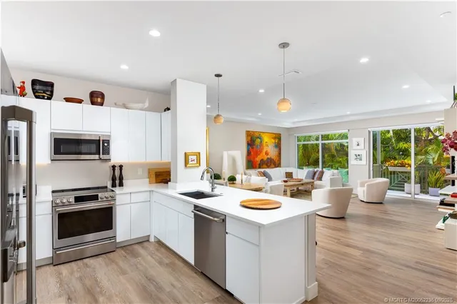 a kitchen with a stove a sink dishwasher a refrigerator and a dining table with wooden floor