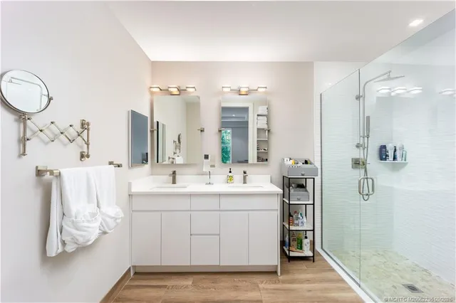 a bathroom with a double vanity sink mirror and shower