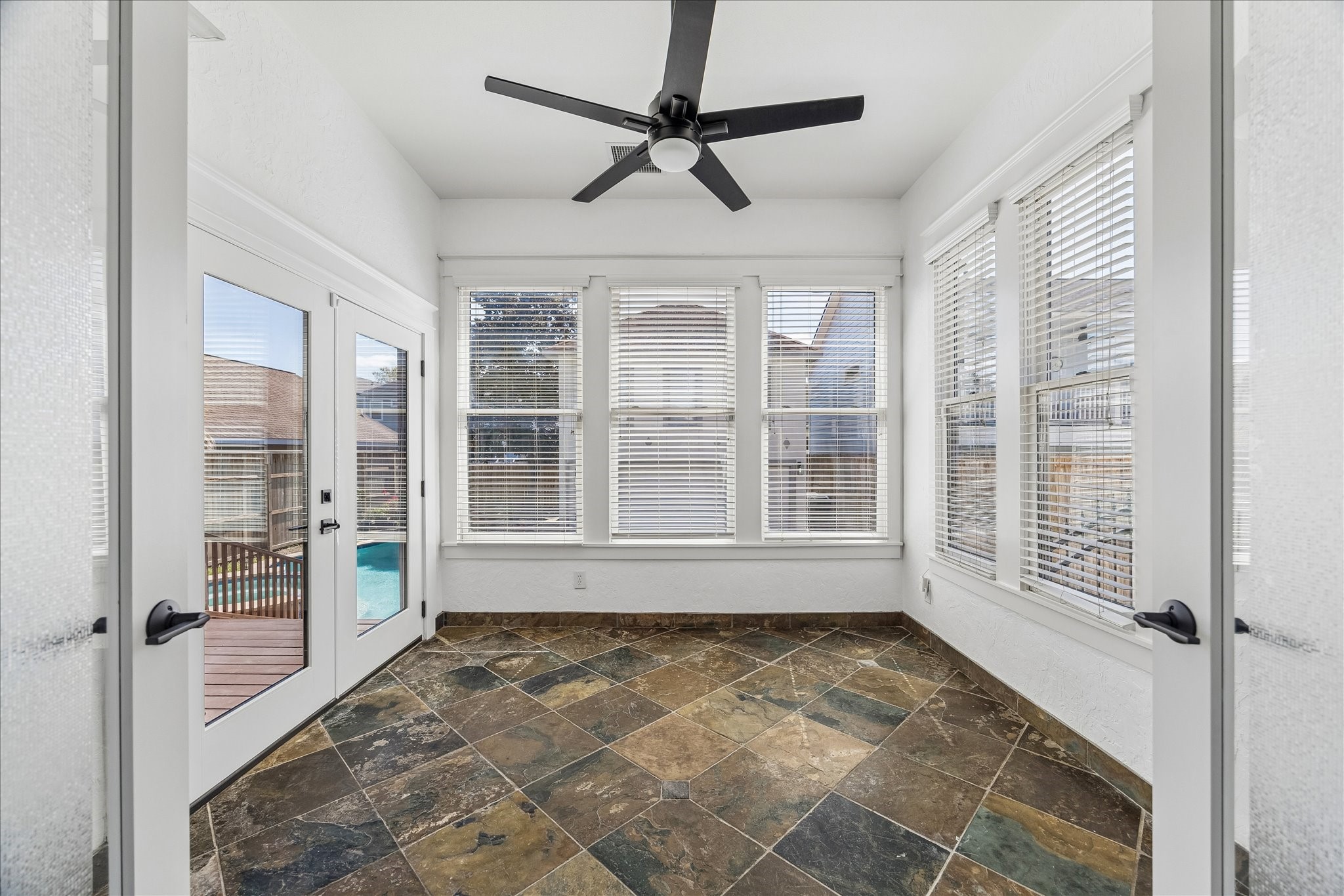 1408 West 23rd Street Houston, TX 77008 - Photo 21 of 40 Bright sunroom with tile flooring, ceiling fan, and wall of windows overlooking the pool and backyard.