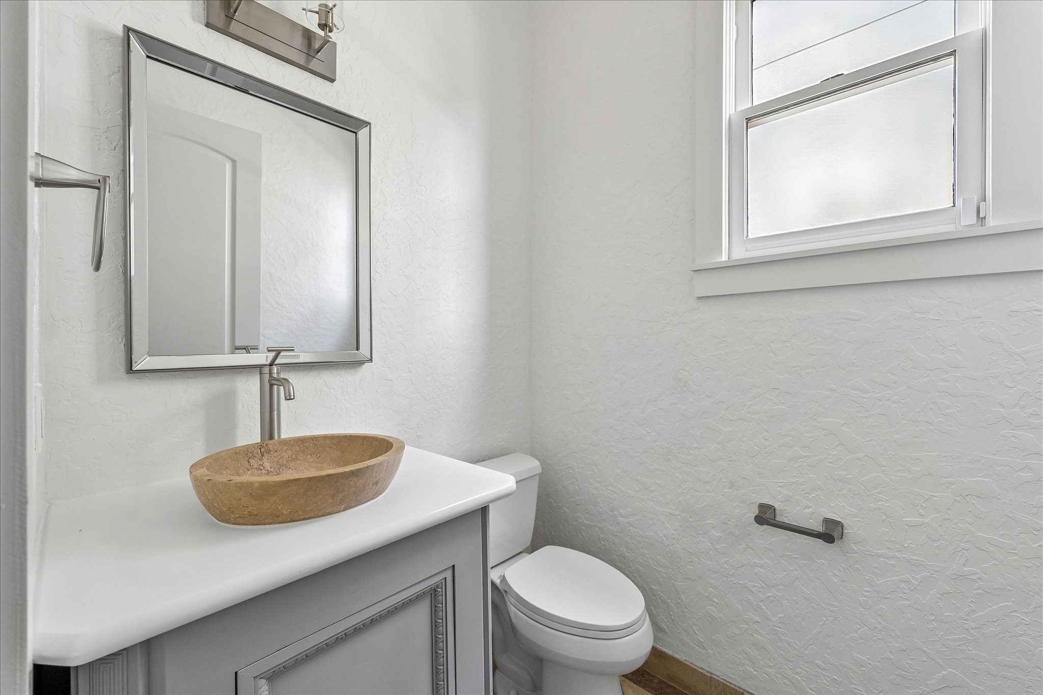 1408 West 23rd Street Houston, TX 77008 - Photo 22 of 40 Stylish powder room featuring a stone vessel sink, sleek fixtures, and natural light from the window.