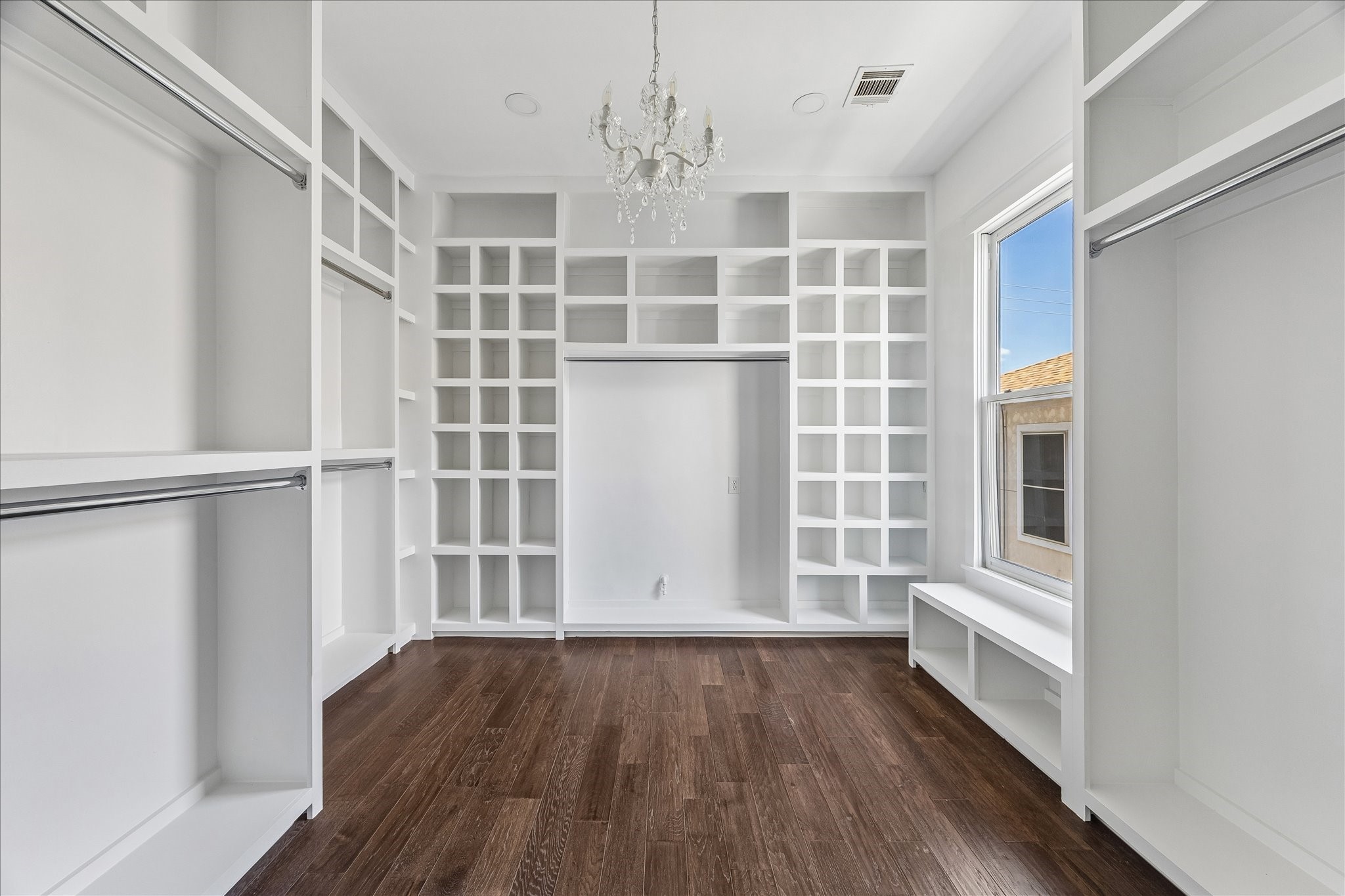 1408 West 23rd Street Houston, TX 77008 - Photo 31 of 40 Expansive custom walk-in closet with extensive built-ins, shelving, hanging space, and elegant chandelier lighting.